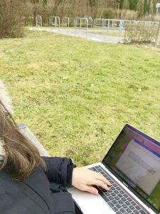 Mit laptop auf einer Parkbank schreiben