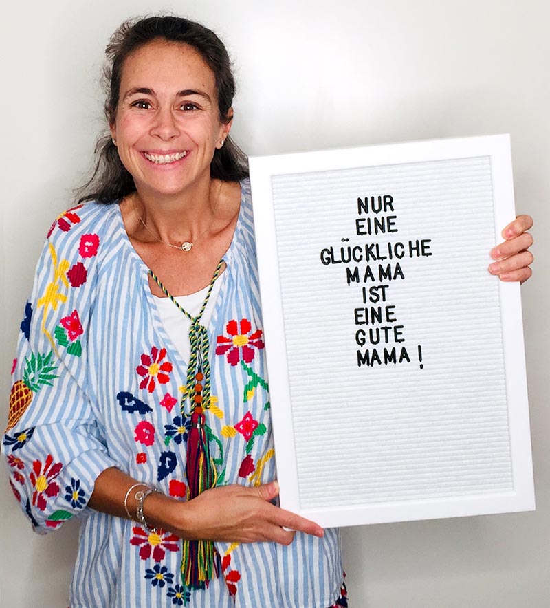 Giulia hält ein Letterboard hoch: "Nur eine glückliche Mama, ist eine gute Mama!"